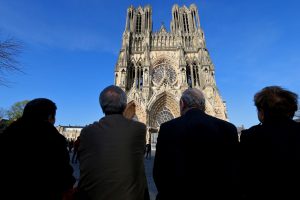 People sit in front of the Reims cathedral as the bells ring at 1650 GMT (1850 Paris time) to mark the exact moment when the fire started at the Notre-Dame de Paris cathedral, in Reims, eastern France, on April 17, 2019. - The bells of French cathedrals were to ring out at 1650 GMT on April 17, 2019 to mark the exact moment when the fire started on April 15, 2019. Paris was struck in its very heart as flames devoured the roof of Notre-Dame, on April 15, 2019, the medieval cathedral made famous by Victor Hugo, its two massive towers flanked with gargoyles instantly recognisable even by people who have never visited the city. (Photo by FRANCOIS NASCIMBENI / AFP / MANILA BULLETIN)