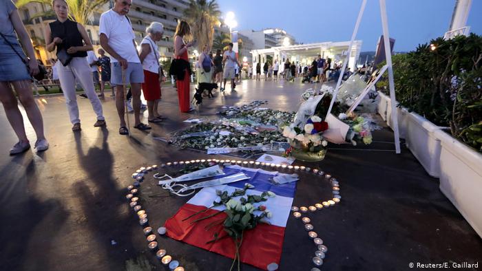 Les gens regardent les hommages des bougies et des fleurs sur la promenade de la promenade à Nice (Reuters / E. Gaillard)