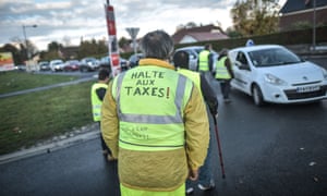 Homme en gilet jaune sur lequel il est écrit 'stop the taxes' en français