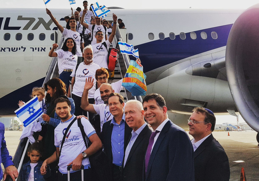 Isaac Herzog poses with French immigrants as they disembark from their aliya flight.
